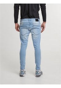 Hele sinised, kitsad teksad koos tuhmunud efektiga, millel on kaks tagataskut ja must silt vöökoha peal. Lisaks hallid tossud.