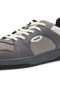 Grey and black leather sneaker with white laces and "HUGO" logo on the side, featuring stitched panel design and perforations.