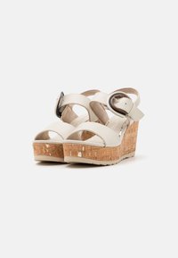 Witte wig-sandalen met een kurken plateau, verstelbare enkelband met een ronde gesp en open te ontwerp. Gladde bovenmateriaal.
