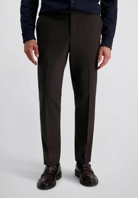 Donkerbruine op maat gemaakte broeken met een gladde textuur en strakke lijnen, gecombineerd met donkerleren loafers met minimaal hardware.