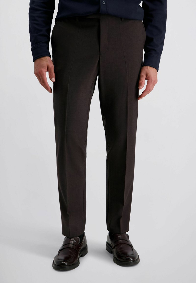 Donkerbruine op maat gemaakte broeken met een gladde textuur en strakke lijnen, gecombineerd met donkerleren loafers met minimaal hardware.