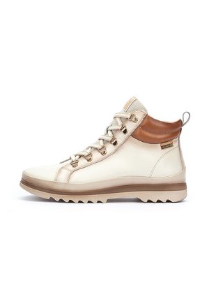 Bottes de randonnée mi-hautes en cuir crème avec un accent en cuir marron clair à la cheville. Elles comportent des œillets métalliques, des lacets texturés et une semelle extérieure en caoutchouc robuste.