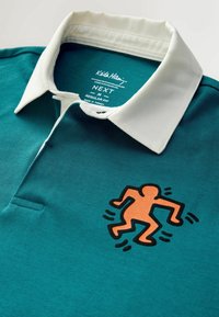 Tyrkysové polo tričko s bílým límečkem. Na přední straně se nachází černá a oranžová grafika karikaturní postavy. Standardní střih, bavlněný materiál.