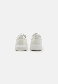 Białe sneakersy o gładkiej skórzanej powierzchni, zaokrąglonym kształcie, wyściełanym kołnierzu oraz wytłoczonym logo „Calvin Klein” na pięcie. Lekkie podeszwy.