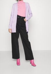 Ljuslila cardigan med öppen front, ribbade manschetter, svarta högmidjade vida jeans och glansiga rosa ankelskod.