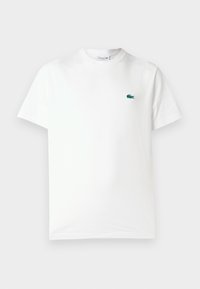 Camiseta de algodón blanca con cuello redondo, mangas cortas y un pequeño logo de cocodrilo bordado en verde en el lado izquierdo del pecho.