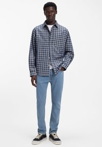 Ruuduline tumesinine ja helehall särkkas, millele on lisatud helesinised teksad ning mustad tossud beežide paeltega. Vabaaja sobivus.