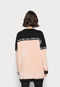 Weicher, übergroßer Pullover in zartem Rosa und Schwarz mit gerippten Bündchen. Verfügt über das "LIU JO"-Logo entlang des schwarzen Streifens an den Schultern.