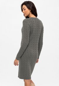Gebreide sweaterjurk in gedempt grijs, met een kabelbrei-textuur, lange mouwen en een rechte silhoeët die boven de knie eindigt.
