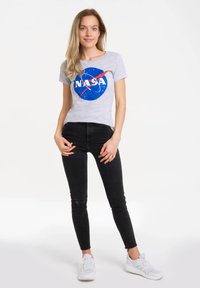 Gray t-shirt featuring a blue NASA logo with white text, paired with black jeans and white sneakers. Simple, casual, and fitted design.