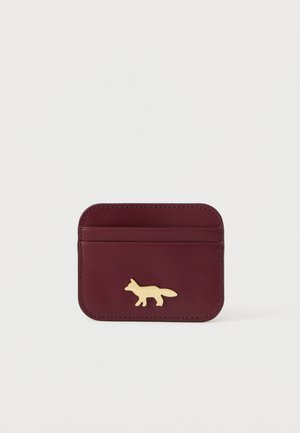 Maroon leather cardholder with a gold fox emblem, featuring slots for cards and a smooth texture; rectangular shape with rounded corners.