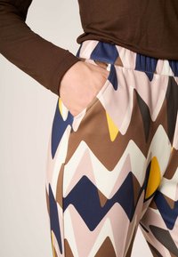 Multifarvede leggings med zigzag mønstre i nuancer af brun, pink, marineblå og gul; letvægtsstof; elastisk talje; sidelomme.