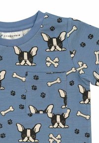 Blå bomull T-shirt med ett upprepande mönster av svarta och vita hundansikten, ben och tassavtryck; inkluderar en framficka.