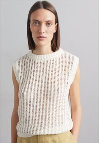 Pletený bezrukávový top v off-white barvě s vertikálním otevřeným pleteným vzorem, žebrovaným kulatým výstřihem a měkkou texturou.