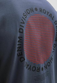 Námořnické modré bavlněné tričko s kruhovou grafikou s červenými vodorovnými pruhy a černým textem "ROYAL DENIM DIVISION."
