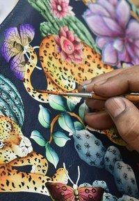Kleurrijk handgeschilderd leren kunstwerk met een luipaard, bloemen en een vlinder, met ingewikkelde details en levendige kleuren op een donkere achtergrond.