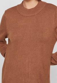Maglione marrone a maglia con collo alto e maniche lunghe, caratterizzato da una texture morbida e motivi sottili nel tessuto.