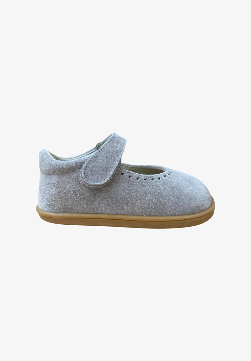 Zapato de ante gris con punta redondeada y correa de velcro. Presenta detalles perforados en la parte delantera y una suela de goma marrón.