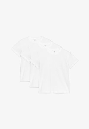 Trois t-shirts blancs unis à manches courtes et col rond, disposés en chevauchement sur un fond blanc.