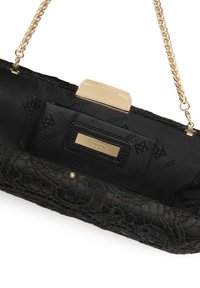 Musta käsilaukku, jossa on pitsikuvio ja satiinipinta. Siinä on kultaiset metalliosat, ketjuhihna ja logolla koristeltu suljettava osa.