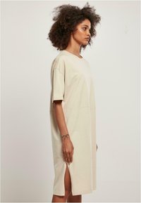 Beige katoenen t-shirt jurk met korte mouwen, met een rechte snit, zijsplitten en een ronde halslijn voor comfort en bewegingsvrijheid.