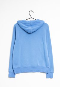 Sudadera con capucha azul claro colgando de un perchero negro, mostrada desde atrás sobre un fondo blanco.