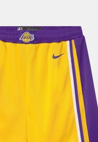 Żółte spodenki koszykarskie z fioletowymi akcentami. Zawierają logo Los Angeles Lakers oraz małe logo Nike. Wykonane z oddychającej siateczki.