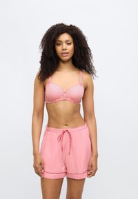 Σετ εσωρούχων ανοιχτού ροζ με σχηματιστό σουτιέν με λεπτομέρειες δαντέλας και αντίστοιχα μπεζ σορτς με πιέτες και κορδόνι στη μέση. Μαλακή, λεία υφή.