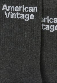 Tamsiai pilkos kojinės su raukšlėta tekstūra, ant šonų užrašyta "American Vintage" baltomis raidėmis. Minkšta megzta medžiaga.