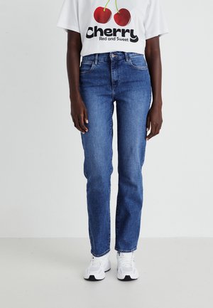 Blue denim jeans with a straight cut, five pockets, and subtle whiskering. Paired with a white graphic t-shirt featuring red cherries.