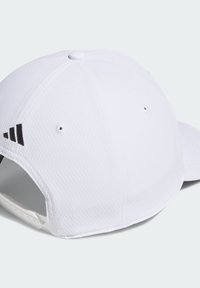 Gorra blanca hecha de tela texturizada con una visera curvada. Presenta detalles de logotipos en negro y orificios de ventilación. Correa ajustable en la parte trasera.