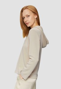 Beige Kapuzenpullover mit weicher Textur, Kordelzugkapuze und Seitentaschen. Entworfen mit einem lässigen Schnitt und langen Ärmeln.