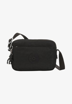 Petit sac bandoulière rectangulaire noir avec sangle réglable, poche zippée à l'avant et porte-clés singe noir attaché.