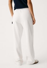 Baltas sporta bikses ar brīvu piegriezumu, elastīgu jostasvietu un gludu tekstūru. Izskatu papildina vienkāršs dizains un bez redzamām rakstām.