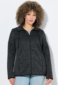 Giacca a zip bicolore, nera e grigia, con texture, dotata di colletto, tasche laterali e maniche lunghe con bordi neri. Tessuto morbido con un design casual.