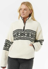 Crème fleece pullover met een zwart-wit patroonband, een halve rits aan de voorkant en zijzakken. Standaard pasvorm met een gestructureerde oppervlakte.