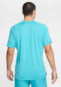 Camiseta desportiva turquesa de mangas curtas, com textura suave e uma bainha curva. Apresenta linhas horizontais subtis na parte de trás.