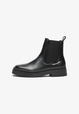 Bottines Chelsea en cuir noir avec panneaux élastiques sur les côtés, finition lisse et semelle en caoutchouc épaisse, dotées d'une languette pour un enfilage facile.