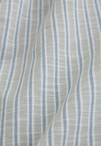 Blødt hvidt stof med lyseblå lodrette striber, der viser bløde folder og fin vævet tekstur.