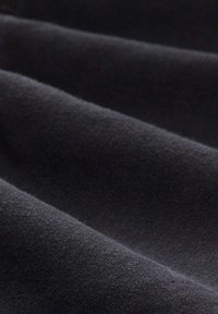 Černá tkanina s jemnou texturou, s nepatrnými záhyby a hladkým povrchem, bez výrazných vzorů nebo kovových prvků.
