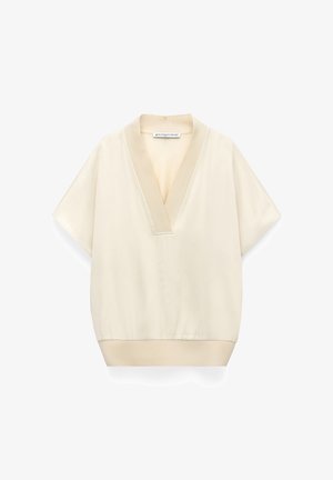Cream short-sleeve blouse with deep V-neck and wide collar, elastic waistband, and soft, smooth fabric by Adolfo Dominguez.