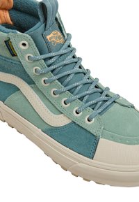 Wysokie trampki Vans w odcieniach teal z białym paskiem po bokach, wzorzystymi sznurowadłami, gumową podeszwą i metką "HydroGuard" odporności na wodę.