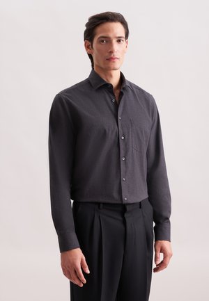 Camicia grigia scura button-up in un tessuto leggero con taschino, maniche lunghe e colletto classico, abbinata a pantaloni neri.