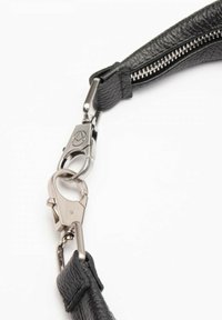 Cinghia in pelle nera con hardware in metallo argentato, dotata di attacco a clip e dettaglio con zip su un lato. Texture liscia, design elegante.