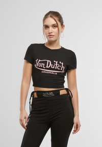 Čierne skrátené tričko s ružovým logom "Von Dutch". V kombinácii s čiernymi nohavicami s pásom ozdobeným kryštálmi.