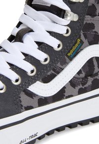Μαύρο και γκρι παπούτσι τύπου high-top με καμουφλάζ, λευκά κορδόνια, λευκή πλαϊνή ρίγα, ετικέτα HydroGuard και σήμανση "ALL-TRAC" στη λευκή σόλα.