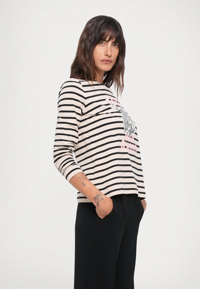 Striped long-sleeve top in beige and black with a central graphic design. Features a rounded neckline and relaxed fit. Casual, lightweight fabric.