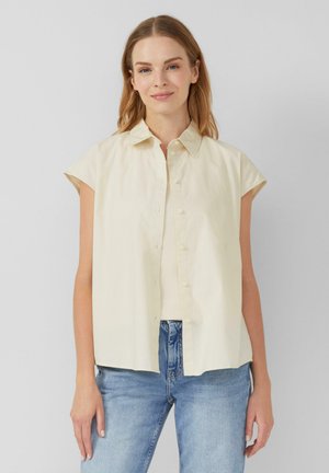 Light beige short-sleeve button-up shirt with a classic collar and relaxed fit. Made of smooth cotton fabric, features a straight hem.