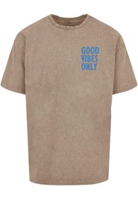 Brun bomuld t-shirt med rund hals, prydet med blå tekst, der står "GOOD VIBES ONLY" på venstre bryst. Glat tekstur.