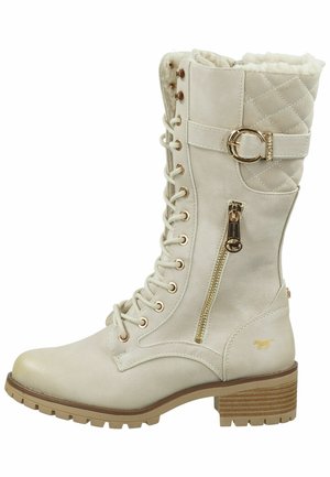 Bottes beiges montant jusqu'aux genoux avec un design matelassé, des accents dorés, un laçage à l'avant, une fermeture éclair sur le côté et une semelle épaisse brune. Doublure en fausse fourrure.